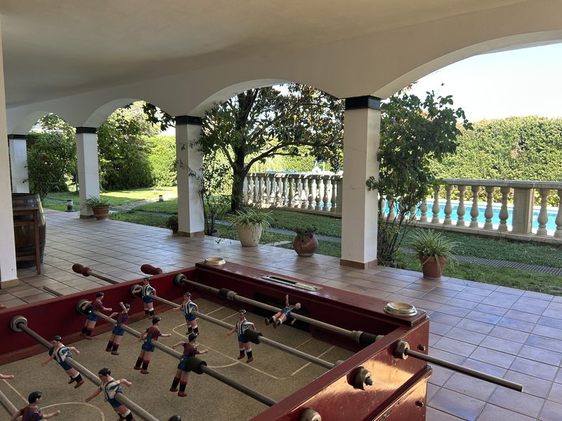 Futbolín bajo los arcos del porche con la piscina al fondo